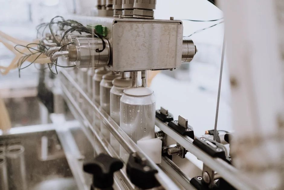 Close-up of an automated can filling machine in a beverage production line. - 广州包装材料机械设备研发企业怎么构建专利壁垒防止竞品抄袭packaging machinery